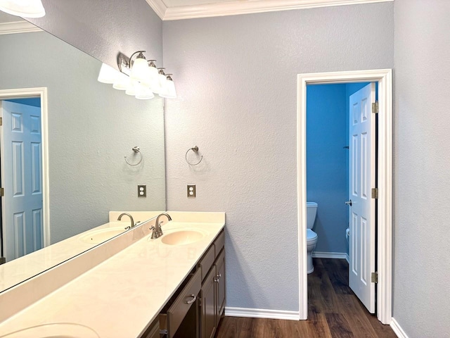 bathroom featuring hardwood / wood-style flooring, crown molding, vanity, and toilet