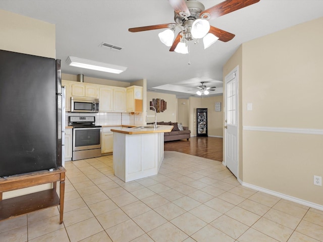 kitchen featuring light tile patterned flooring, sink, tasteful backsplash, appliances with stainless steel finishes, and kitchen peninsula