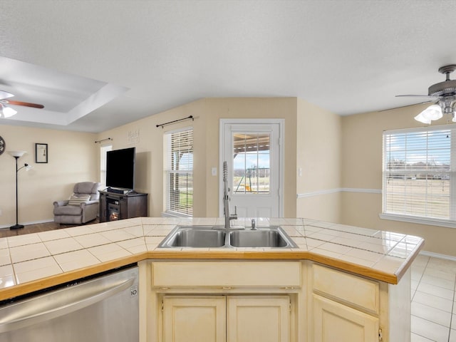 kitchen with sink, stainless steel dishwasher, tile counters, and ceiling fan