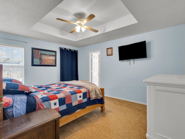 carpeted bedroom with ceiling fan and a raised ceiling