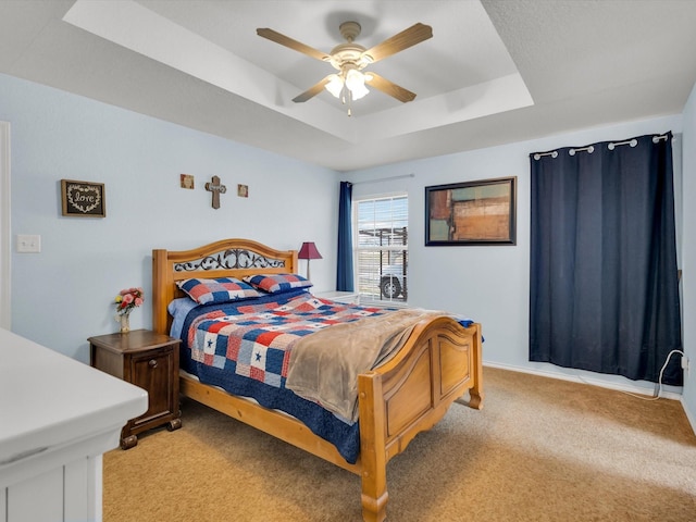 bedroom with a raised ceiling, light carpet, and ceiling fan