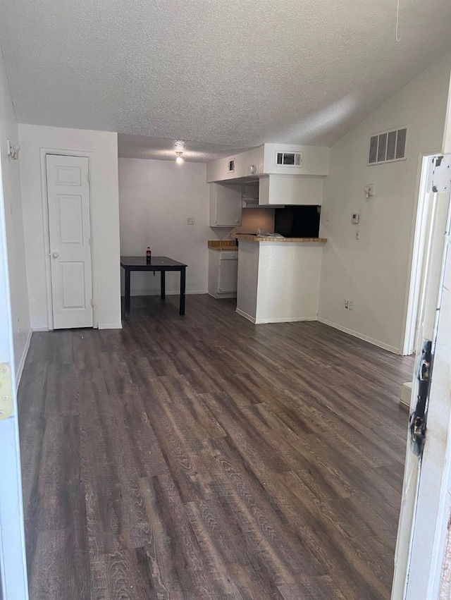 unfurnished living room with vaulted ceiling, dark wood-type flooring, and a textured ceiling