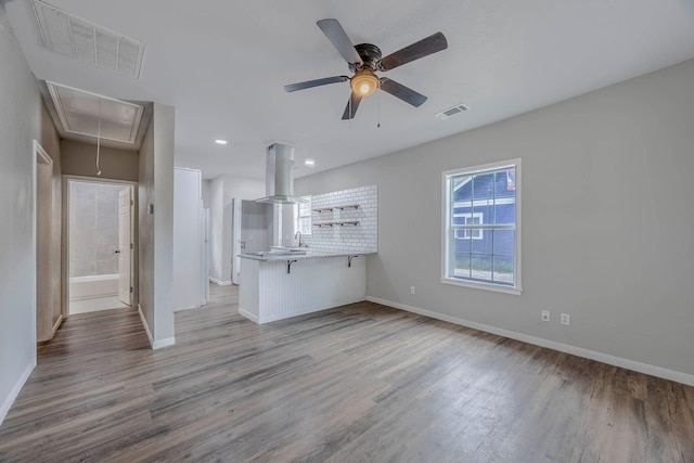 unfurnished living room featuring hardwood / wood-style flooring, sink, and ceiling fan