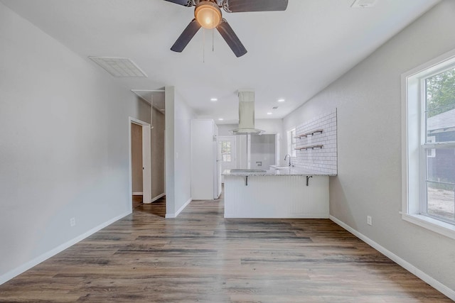 unfurnished living room featuring dark wood-type flooring, ceiling fan, plenty of natural light, and sink