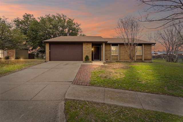 view of front of home featuring a garage, driveway, brick siding, and a lawn