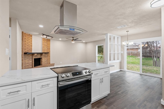 kitchen featuring island range hood, white cabinets, stainless steel electric range oven, open floor plan, and hanging light fixtures