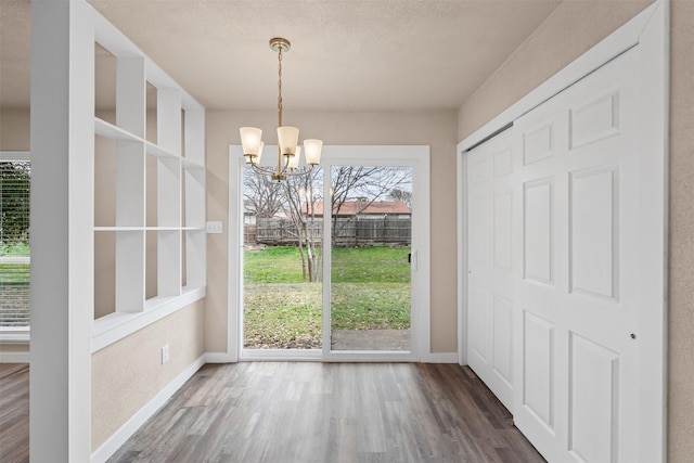 doorway to outside with baseboards, dark wood finished floors, and a notable chandelier