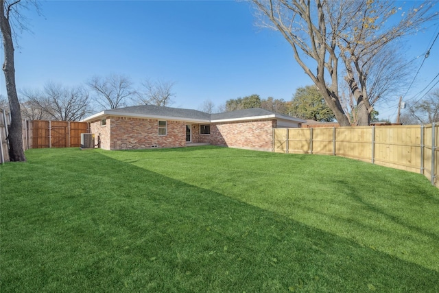 rear view of property with central AC unit and a lawn