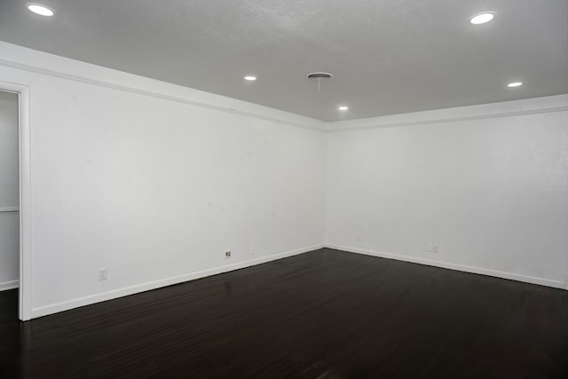 spare room featuring baseboards, dark wood finished floors, visible vents, and recessed lighting