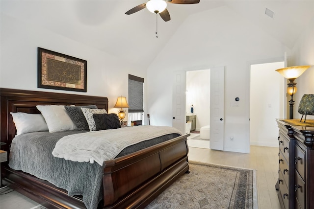 bedroom featuring ceiling fan, high vaulted ceiling, ensuite bathroom, and light hardwood / wood-style floors