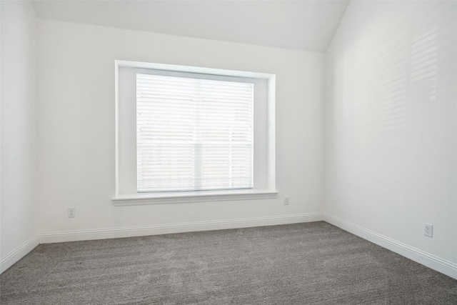 carpeted empty room featuring vaulted ceiling