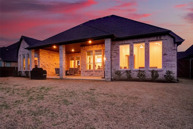 back house at dusk featuring a patio area