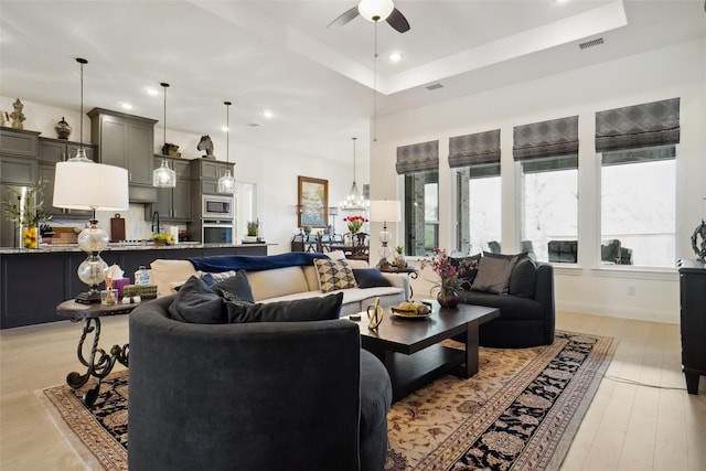 living room featuring a raised ceiling, a wealth of natural light, and ceiling fan