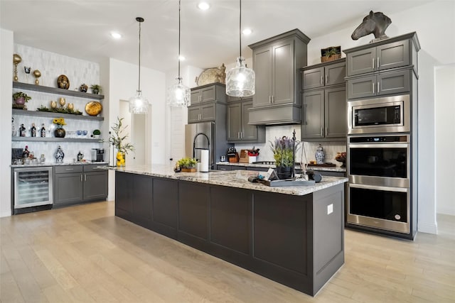 kitchen with appliances with stainless steel finishes, pendant lighting, sink, beverage cooler, and light stone counters