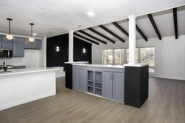 kitchen featuring a center island, light countertops, stainless steel microwave, and gray cabinetry