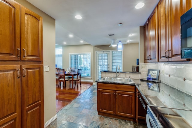 kitchen with pendant lighting, sink, decorative backsplash, ceiling fan, and kitchen peninsula