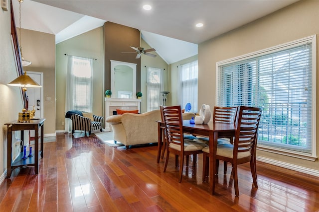 dining area with lofted ceiling, dark hardwood / wood-style floors, a tiled fireplace, and plenty of natural light