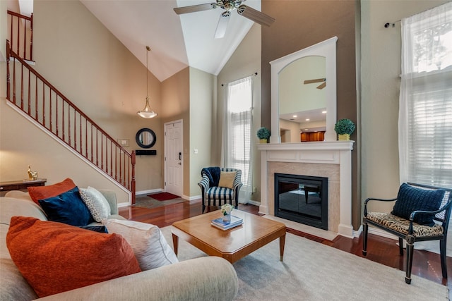 living room featuring dark hardwood / wood-style flooring, a high end fireplace, high vaulted ceiling, and ceiling fan