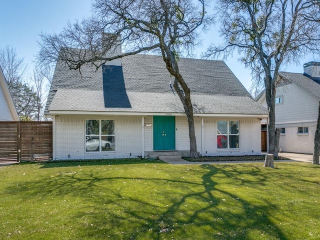 view of front of property with roof with shingles, brick siding, a chimney, and a front yard