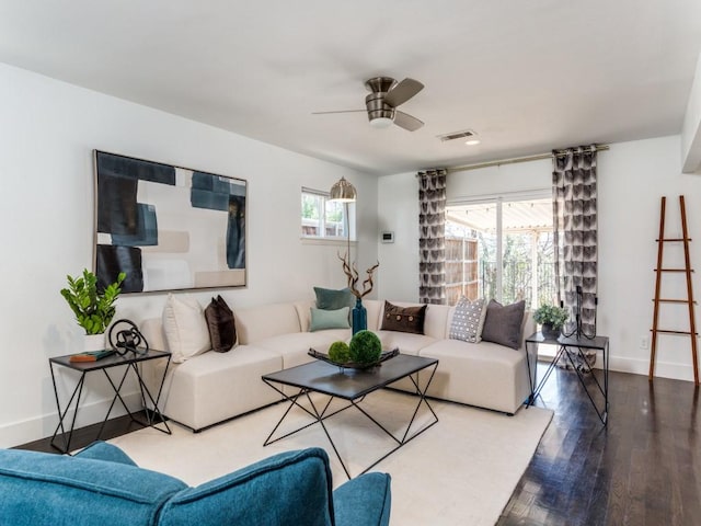 living area featuring baseboards, visible vents, ceiling fan, and wood finished floors