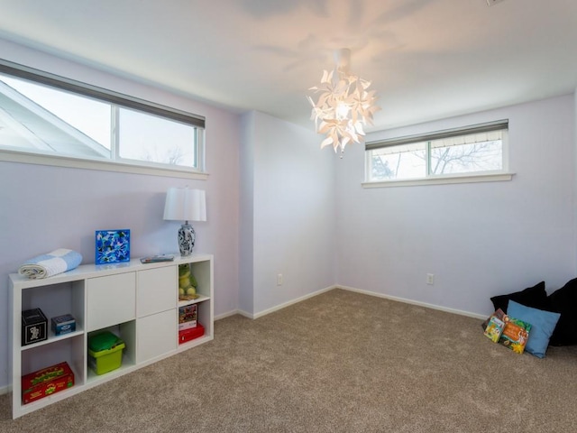 playroom with a wealth of natural light, carpet flooring, baseboards, and an inviting chandelier