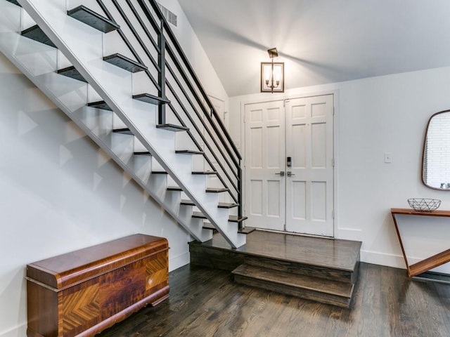 foyer entrance with stairs, wood finished floors, and baseboards