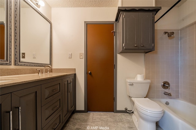 full bathroom with tile patterned floors, toilet, tiled shower / bath, a textured ceiling, and vanity