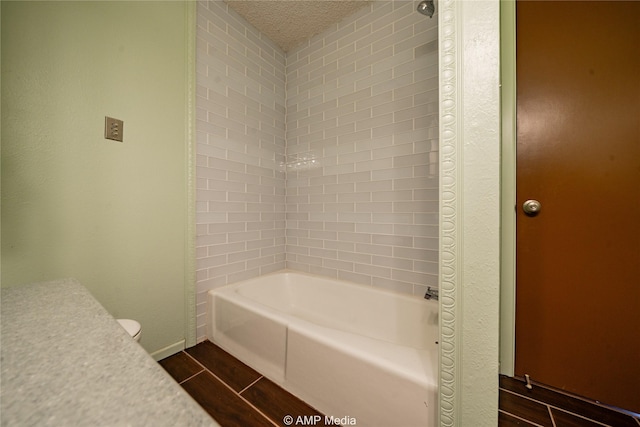 bathroom with tiled shower / bath and a textured ceiling