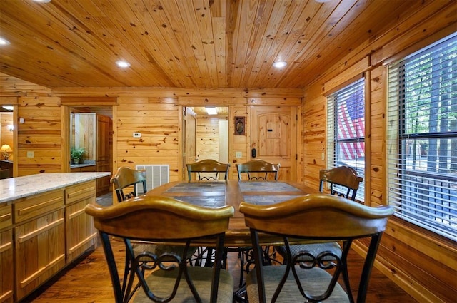 dining area with dark hardwood / wood-style flooring, wooden ceiling, and wooden walls