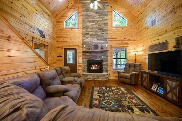 living room with hardwood / wood-style flooring, plenty of natural light, a stone fireplace, and wood walls