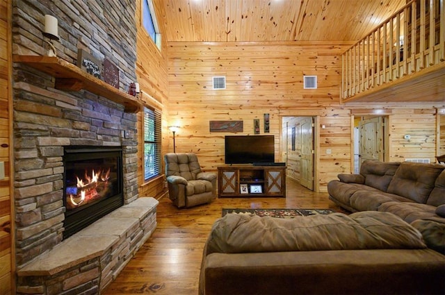 living room featuring wood walls, a fireplace, light hardwood / wood-style floors, and wooden ceiling