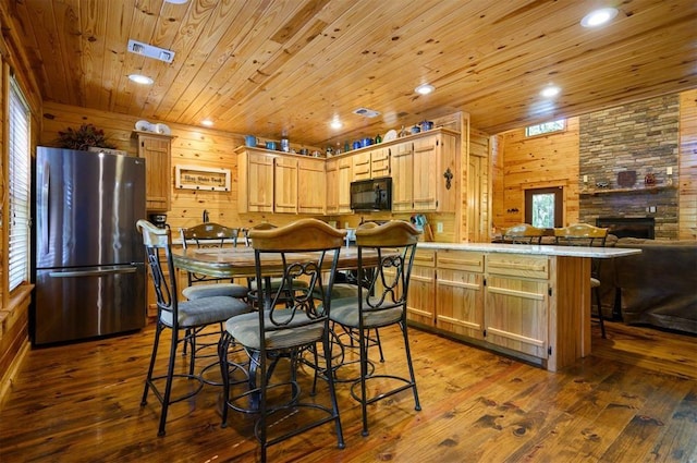 kitchen with hardwood / wood-style floors, wood walls, stainless steel fridge, kitchen peninsula, and wooden ceiling