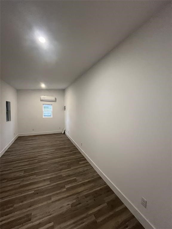 basement with a wall unit AC and dark hardwood / wood-style flooring