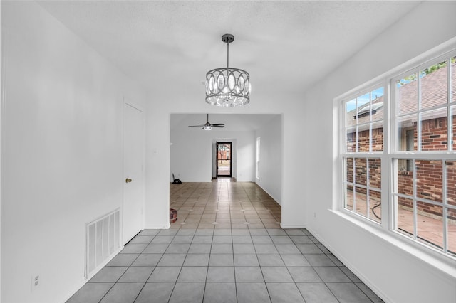 hallway featuring tile patterned floors, a chandelier, and a textured ceiling