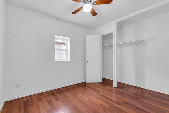 unfurnished bedroom with a textured ceiling, wood-type flooring, a closet, and ceiling fan