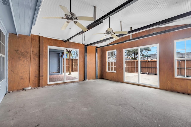 empty room with vaulted ceiling with beams, ceiling fan, and wood walls