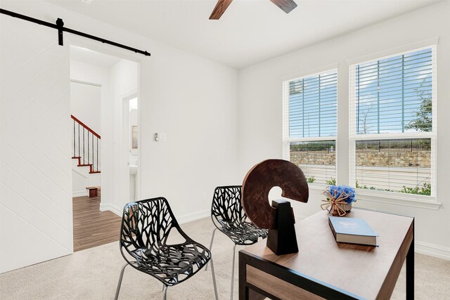 sitting room featuring ceiling fan, a barn door, and carpet