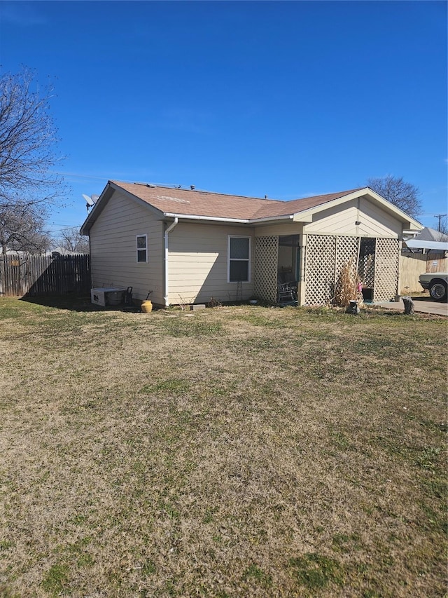 rear view of house featuring fence and a yard