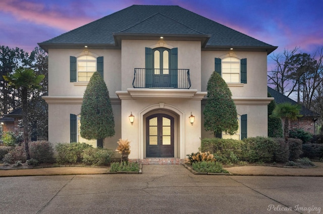 french country home with french doors and a balcony