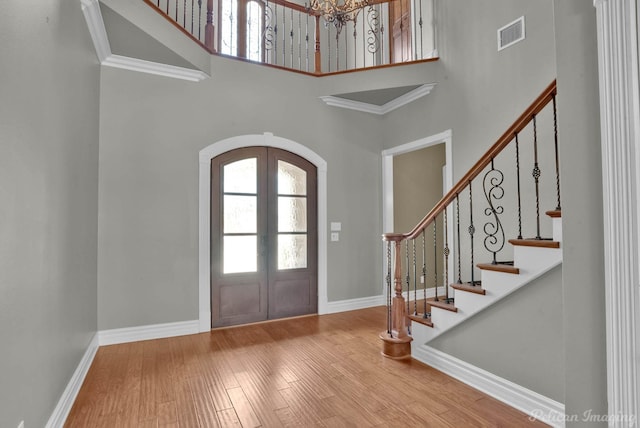 entrance foyer with french doors, wood-type flooring, and a high ceiling