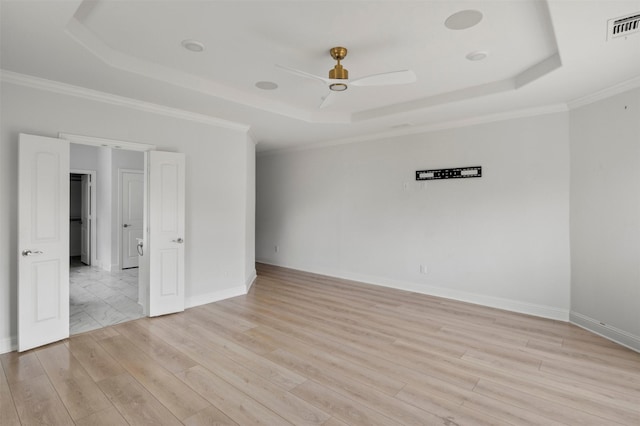 spare room with ceiling fan, ornamental molding, a tray ceiling, and light hardwood / wood-style floors