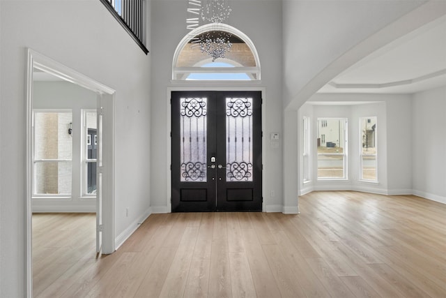 entrance foyer with an inviting chandelier, plenty of natural light, and light wood-type flooring