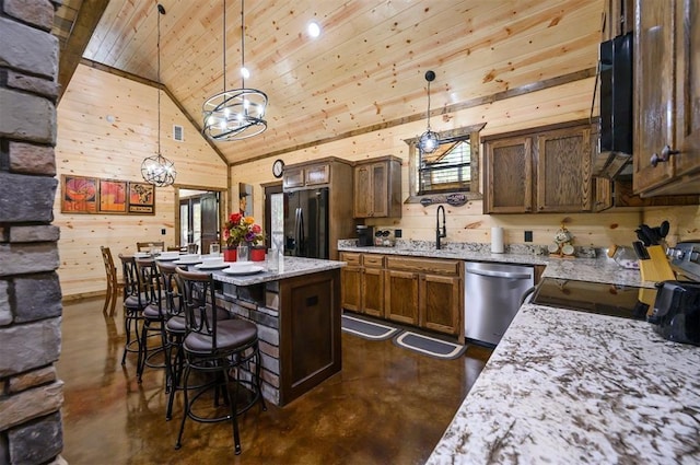 kitchen with sink, hanging light fixtures, black refrigerator, dishwasher, and light stone countertops