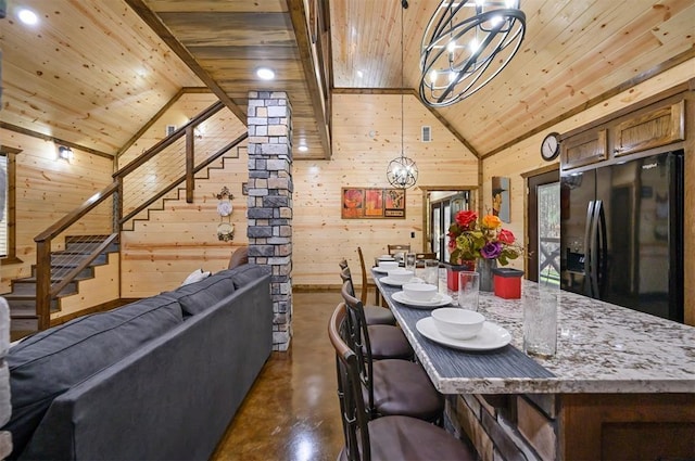 dining space with wood ceiling, wooden walls, and high vaulted ceiling