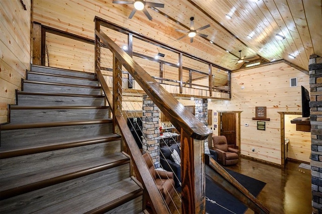 staircase with lofted ceiling, wooden ceiling, ceiling fan, and wood walls