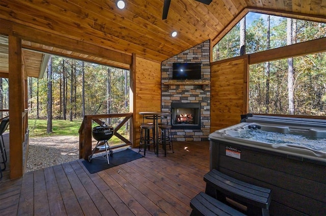 sunroom / solarium with lofted ceiling, plenty of natural light, wooden ceiling, and an outdoor stone fireplace