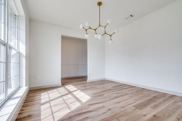 empty room with a chandelier and light wood-type flooring