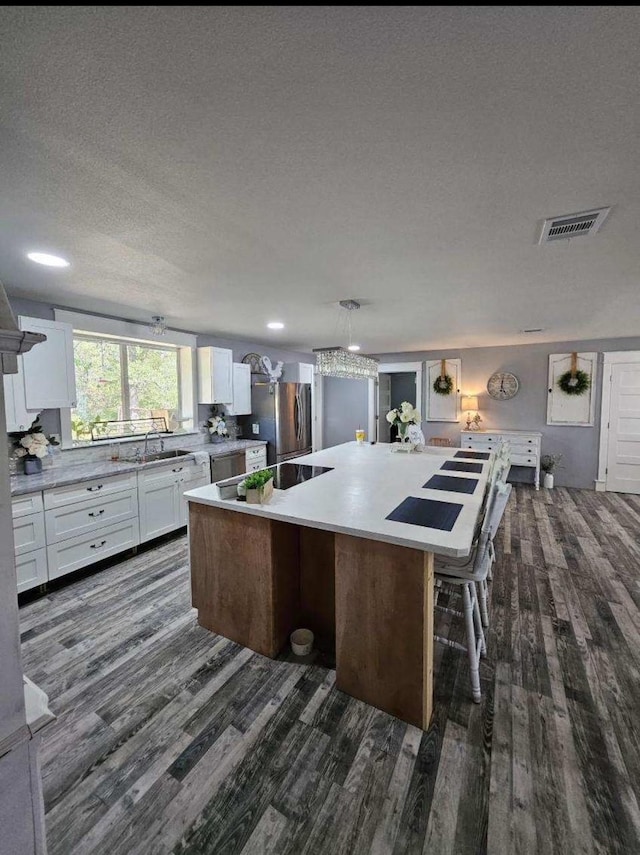 kitchen featuring pendant lighting, white cabinets, a kitchen breakfast bar, a large island, and stainless steel appliances