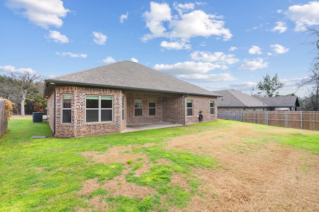 rear view of house with central AC unit, a patio area, and a lawn