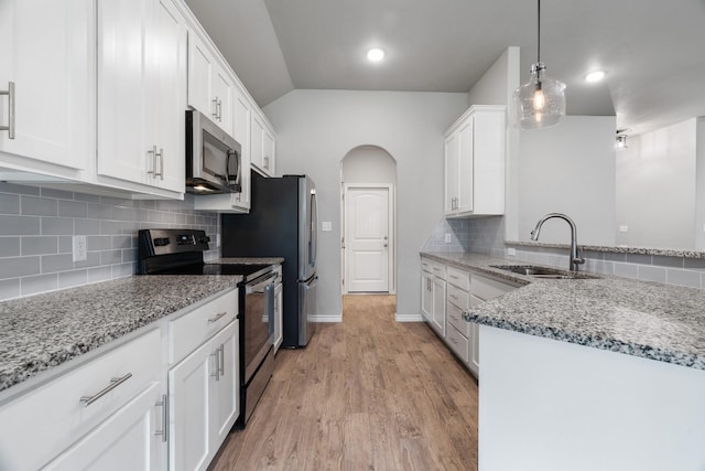 kitchen with decorative light fixtures, white cabinetry, sink, light stone counters, and stainless steel appliances